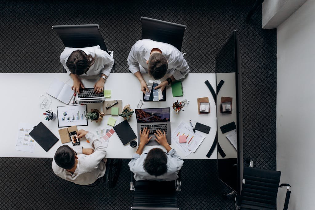 Teamwork in modern office with laptops, charts, and electronic devices from above.